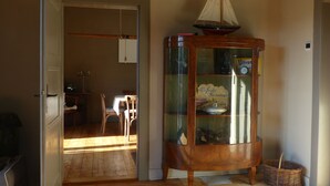 Une pièce comprenant un meuble en bois contenant une maquette de bateau, une horloge et un panneau.