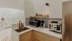 Eine kleine Küche mit Spüle, Mikrowelle, Toaster und Kaffeemaschine.