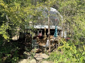 Un espacio al aire libre rústico con una hamaca, sillas y una pequeña mesa.