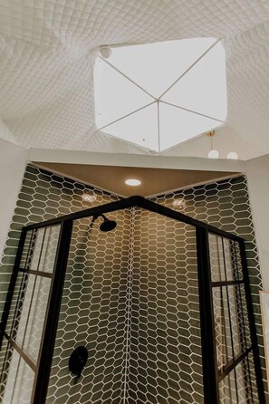 A room with a geometric ceiling design, a hexagonal patterned wall, and a skylight. - Whispering Waters: Dome Getaway (Cosby)