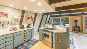 A modern kitchen with a central island, built-in appliances, and a large window overlooking a deck.