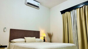 A hotel room with a bed, a bedside lamp, a wall-mounted air conditioner, and a window with curtains. - OFFER Excellent Private House, Garden, BBQ, Garage.  (Ciudad Valles)