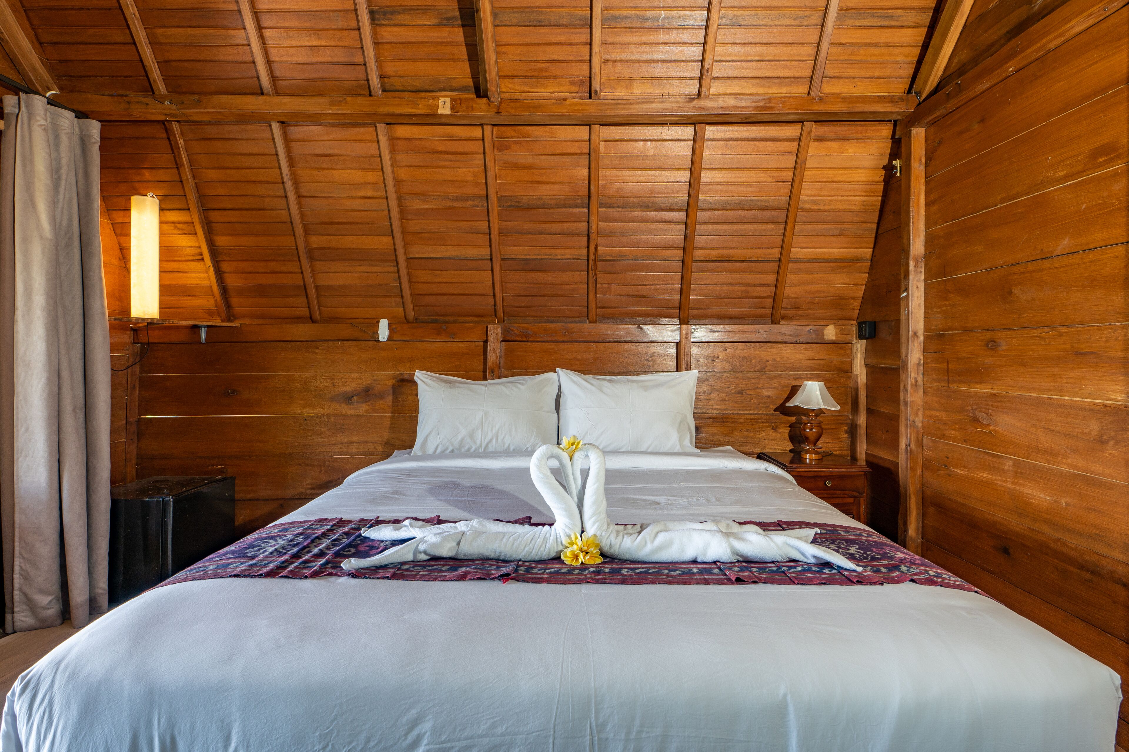 A wooden-paneled room with a bed, a nightstand, and a lamp.