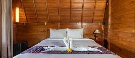 A wooden-paneled room with a bed, a nightstand, and a lamp.