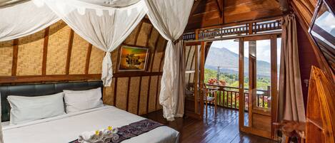 Un dormitorio con una cama grande, paredes de madera, un balcón con vistas y un cuadro en la pared.