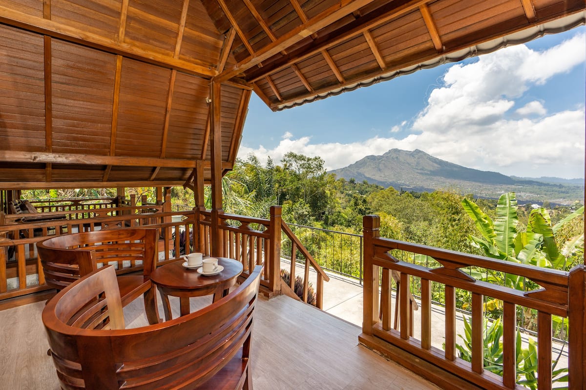 A wooden deck with a table and chairs, overlooking a mountainous landscape.
