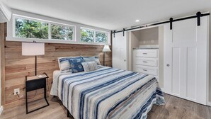 A bedroom with a bed, bedside table, lamp, wardrobe, and a window with a view of trees. - Indian Point Cabin 4 near Silver Dollar City, Table Rock Lake & Branson (Branson)