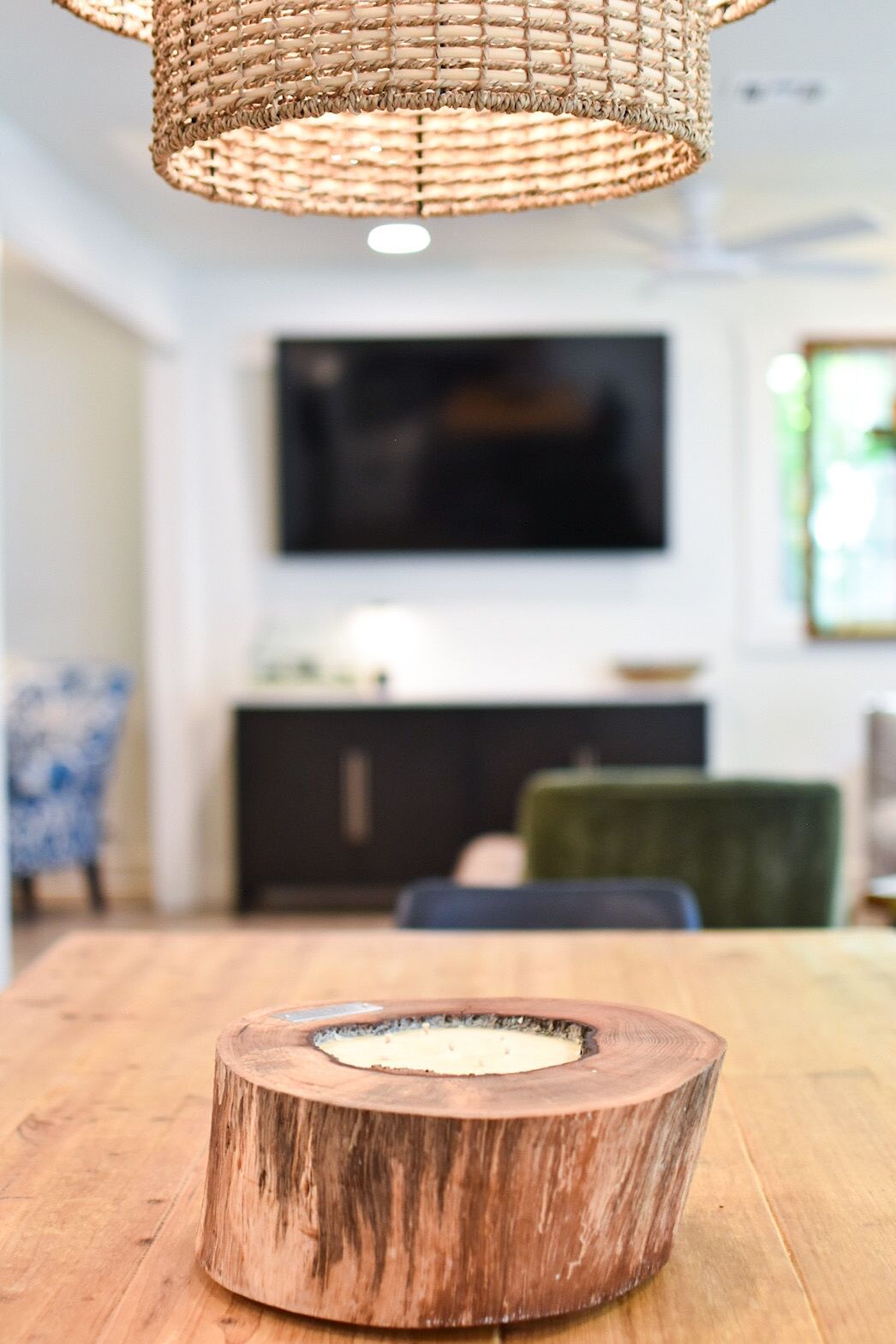 Ein Holztisch mit einer Aussparung in der Mitte in einem modernen Wohnzimmer, im Hintergrund ein Fernseher und ein grüner Sessel.