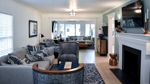 A living room with a fireplace, a television, and a sofa set. - Renovated Historic 5 Bedroom Home Close to OU Campus! (Norman)