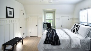 A bedroom with a bed, a bench, a ceiling fan, and a window with blinds. - Renovated Historic 5 Bedroom Home Close to OU Campus! (Norman)