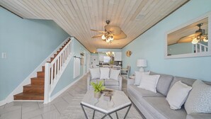 A spacious living room with a wooden staircase, a dining area, and a kitchen in the background. - Waterfront views! 3 BR Walk to beach, Pool, Dock (Fort Walton Beach)