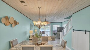 A dining area with a marble table, cushioned chairs, a chandelier, and a view of the outdoors. - Waterfront views! 3 BR Walk to beach, Pool, Dock (Fort Walton Beach)