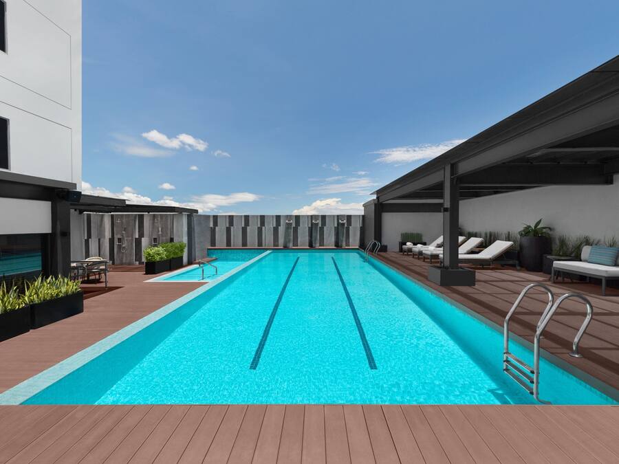 Una piscina moderna al aire libre con agua azul cristalina, rodeada de un deck de madera y sillas de descanso.