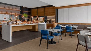 Un comedor moderno con una isla central, sillas azules y grises, y mesas de madera.