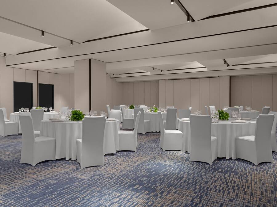 A conference room with round tables, white chairs, and a blue carpet.