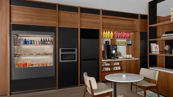 Una cocina moderna con electrodomésticos integrados, un refrigerador lleno de bebidas y un comedor con una mesa redonda y sillas.