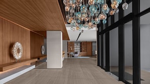 Un interior moderno con un mostrador de recepción de madera, un área de comedor y una cocina al fondo.