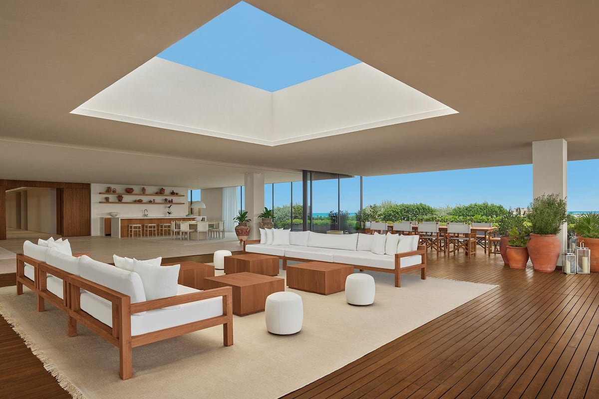 A spacious living area with a high ceiling and skylight, wooden flooring, and a view of the ocean.