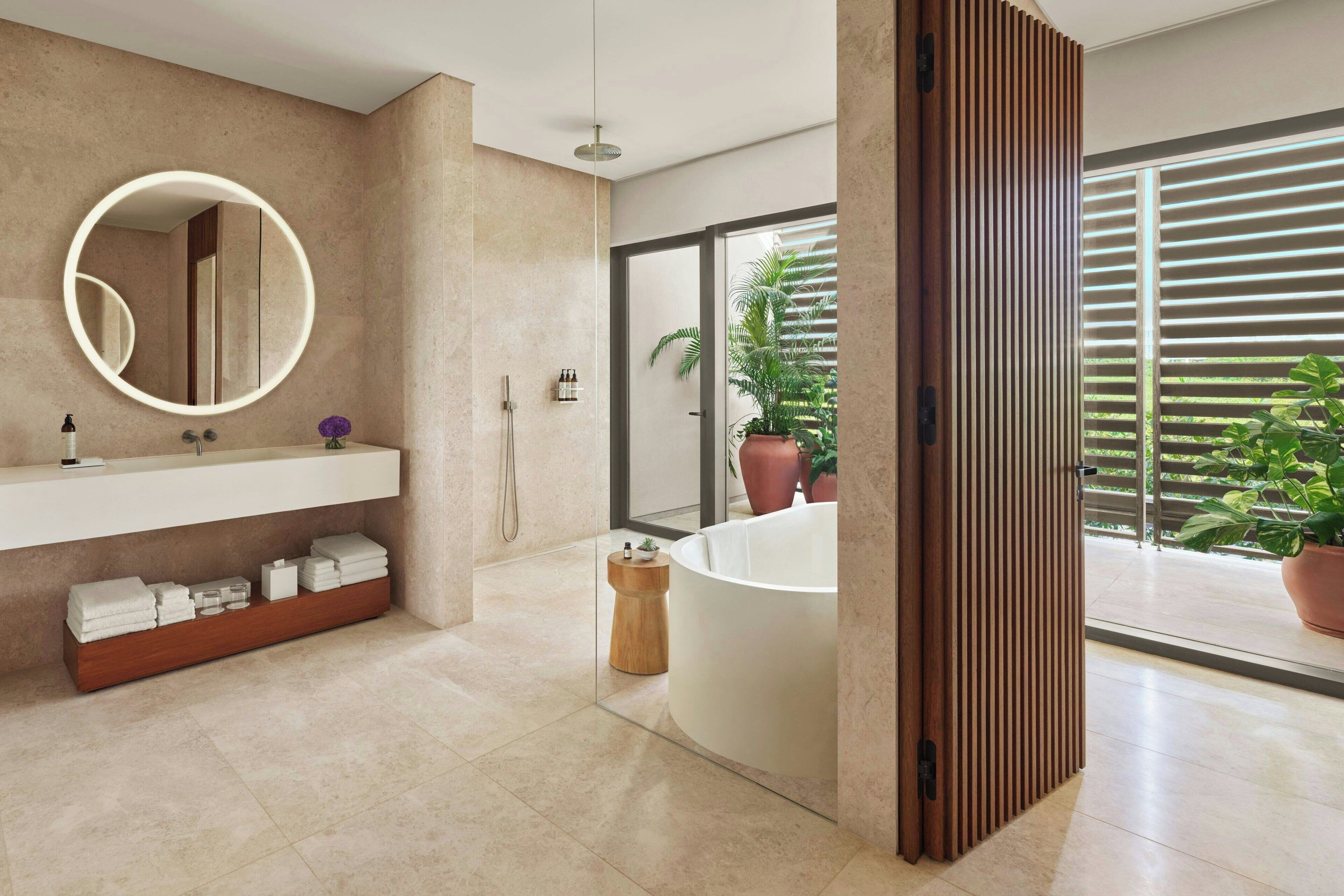 Un baño moderno con un espejo grande, una bañera independiente y un tocador con toallas.