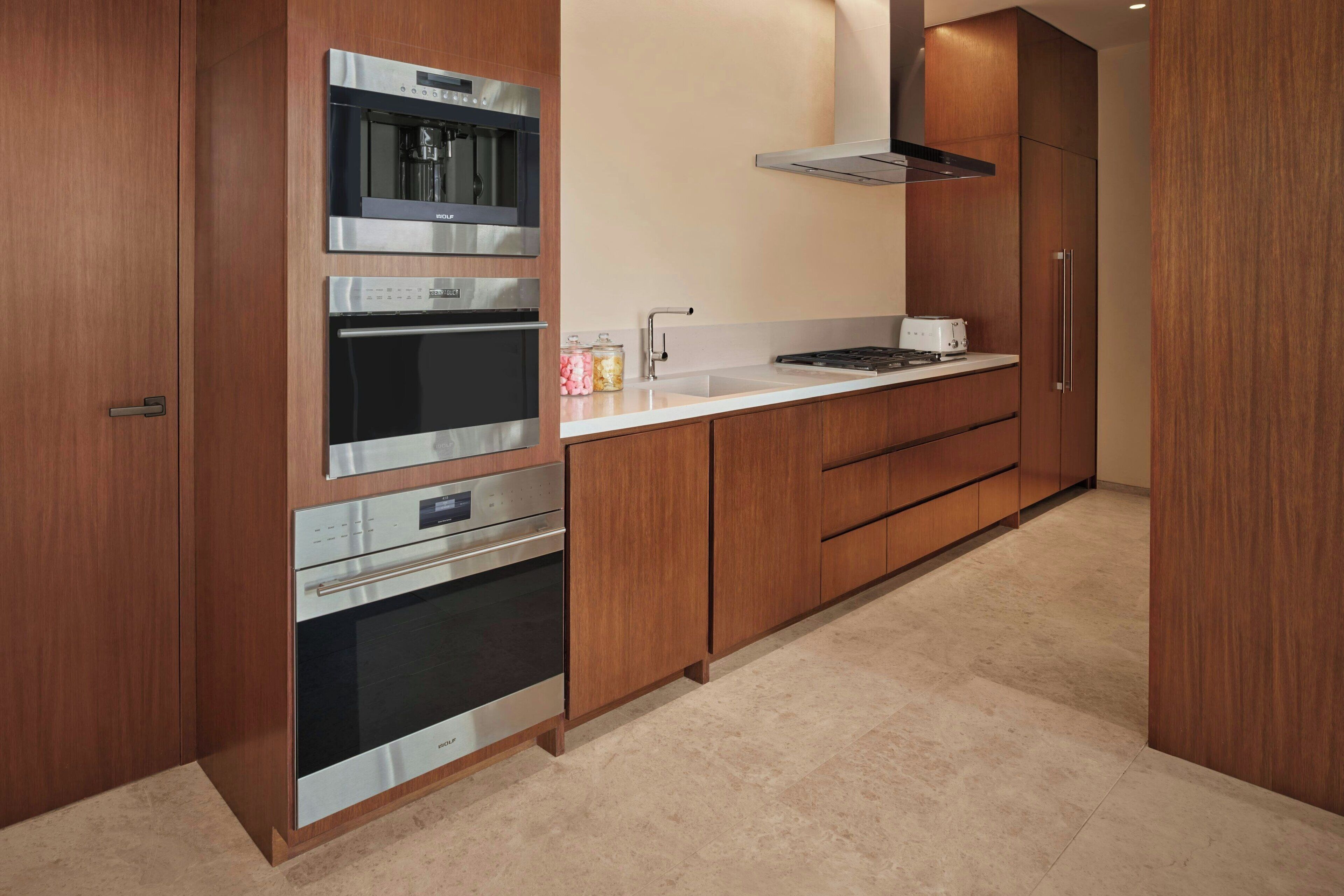 A modern kitchen with stainless steel appliances, wooden cabinets, and a white countertop.