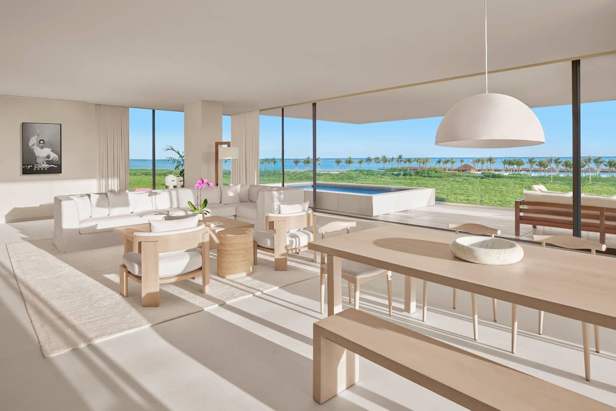 A spacious living area with a large window overlooking a pool and beach.