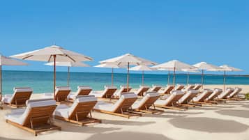 En la playa, arena blanca, camas de playa, sillas reclinables de playa