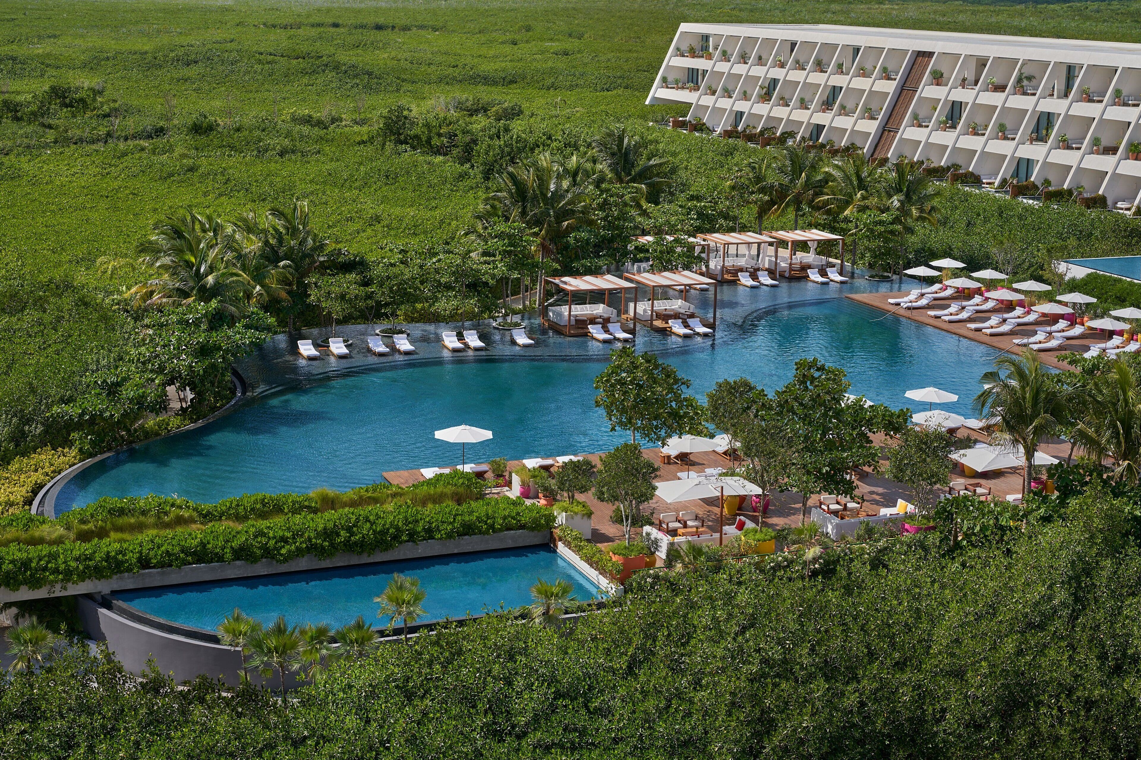 Um resort com uma piscina grande, áreas de descanso e um edifício moderno com varandas.