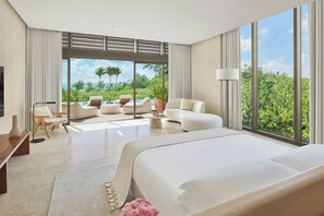 A modern hotel room with a large bed, a seating area with a view of the ocean, and large windows. - The Riviera Maya EDITION At Kanai (Playa del Carmen)