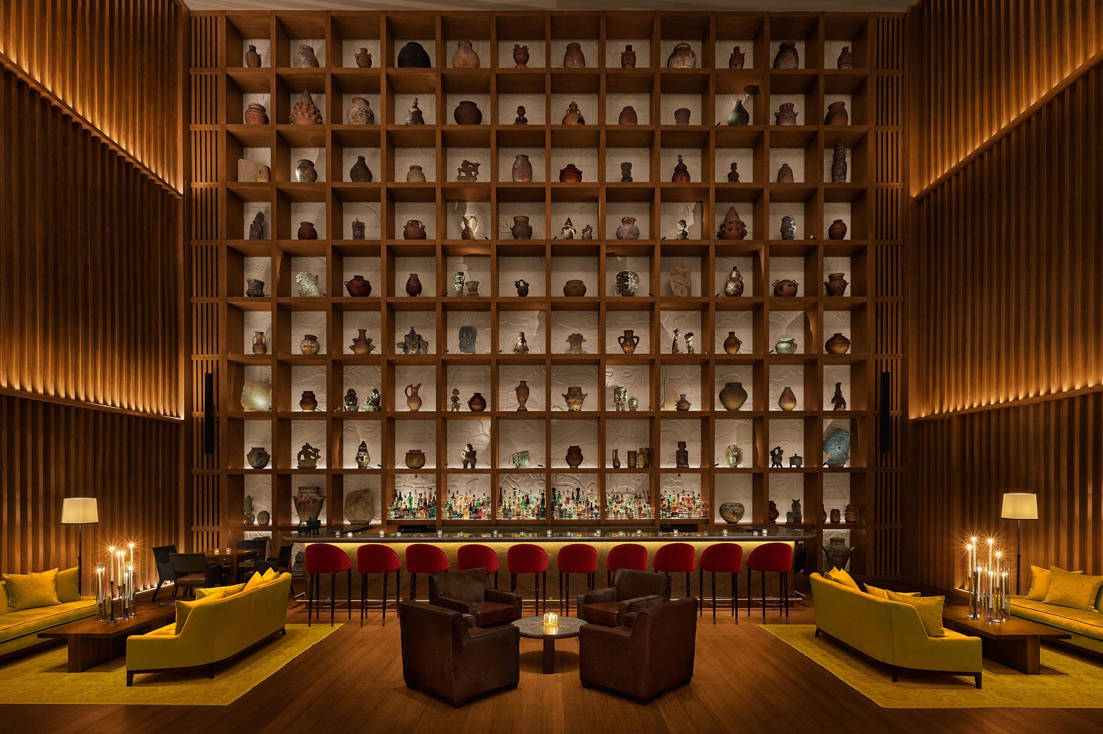 A bar area with multiple seating options and a wall of shelves displaying various items.