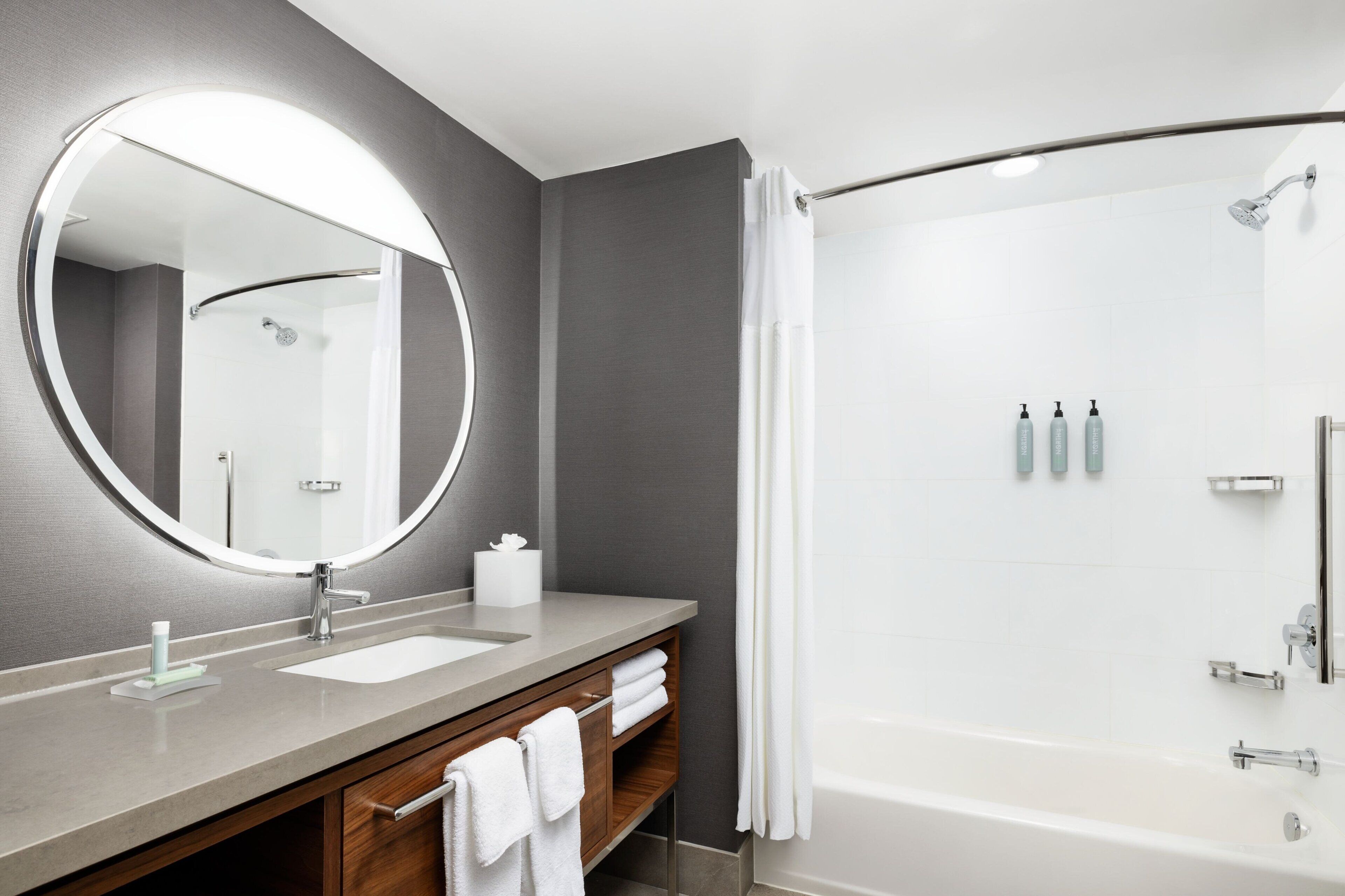 A modern bathroom with a large mirror, a sink, a shower, and a bathtub.