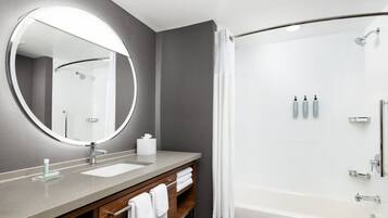A modern bathroom with a large mirror, a sink, a shower, and a bathtub.