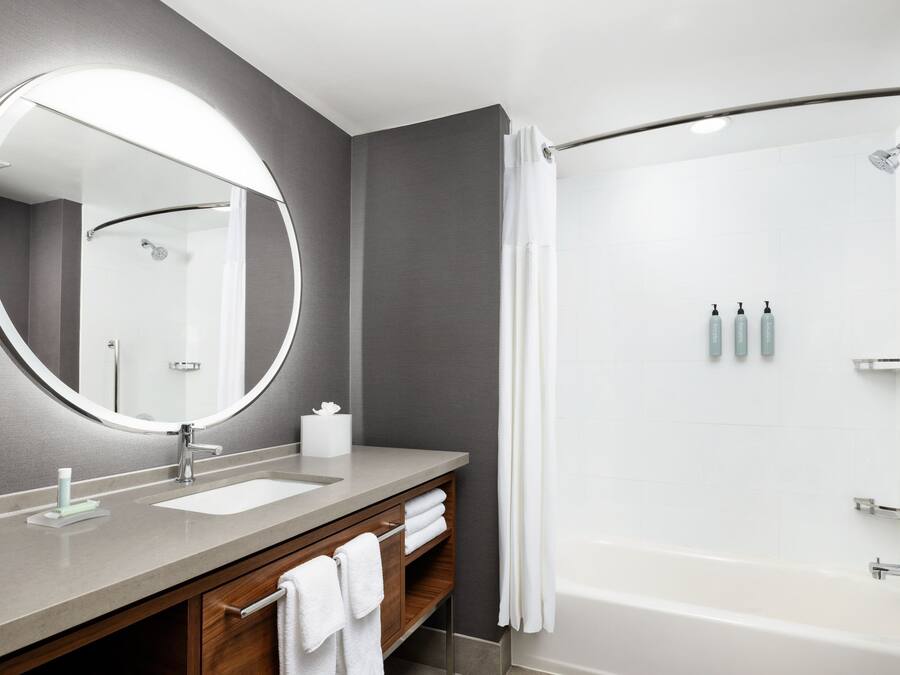 A modern bathroom with a large mirror, a sink, a shower, and a bathtub.