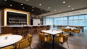 A modern restaurant with a bar area, wooden flooring, and yellow chairs. - Courtyard By Marriott New Castle (New Castle)