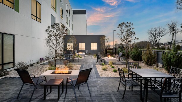 An outdoor patio with fire pits, seating, and a view of a modern building. - Courtyard By Marriott New Castle (New Castle)