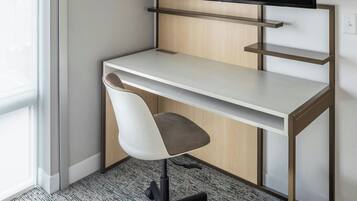 A modern office desk with a flat-screen monitor, a white chair, and a carpeted floor.