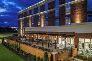 A multi-story hotel with a covered outdoor patio area, large windows, and a brick facade.