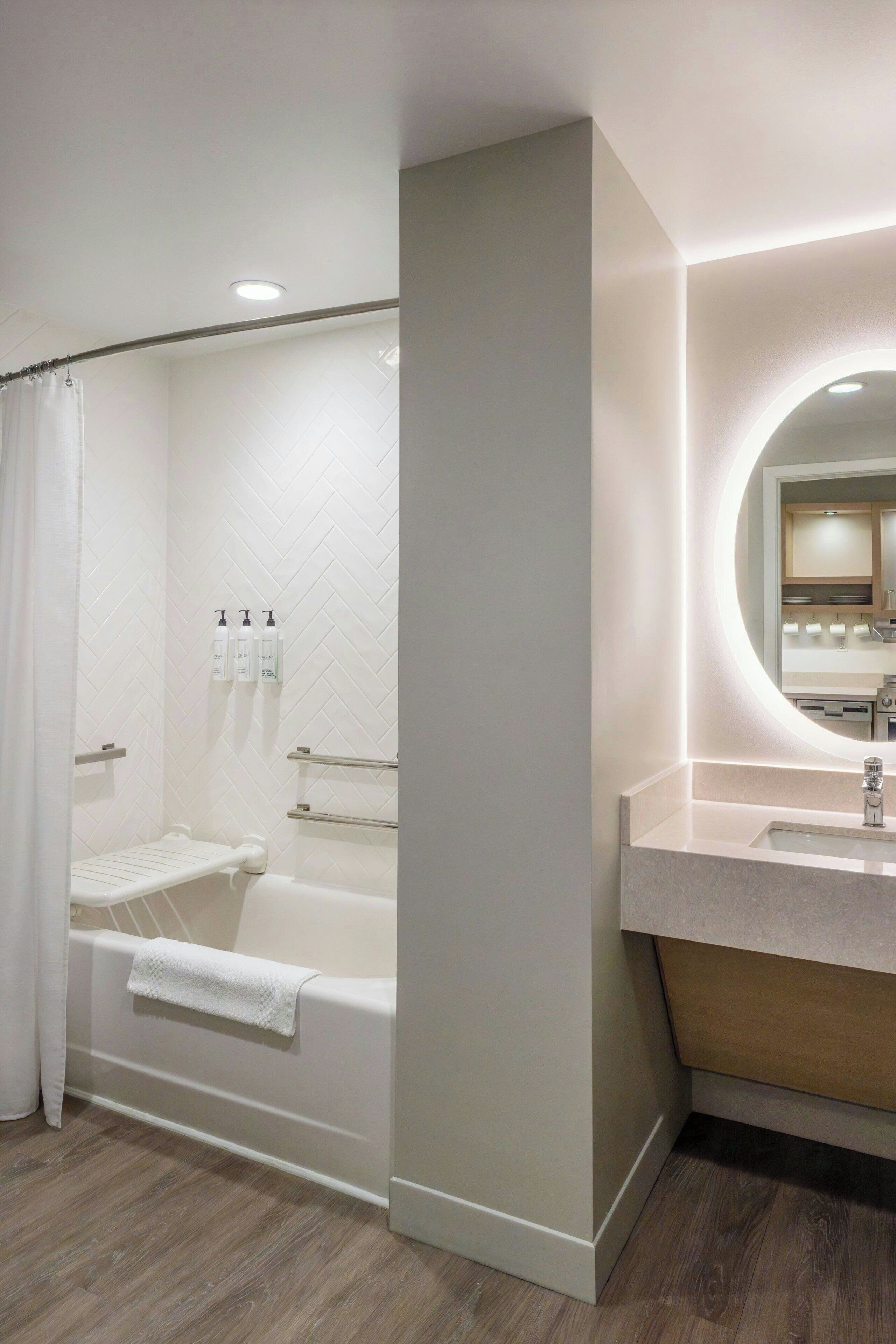 A modern bathroom with a bathtub, a vanity with a mirror, and a shower area.