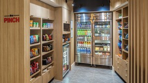 A well-lit, modern pantry area with wooden cabinets and a refrigerated section stocked with beverages and snacks. - Towneplace Suites By Marriott Canfield (Canfield)