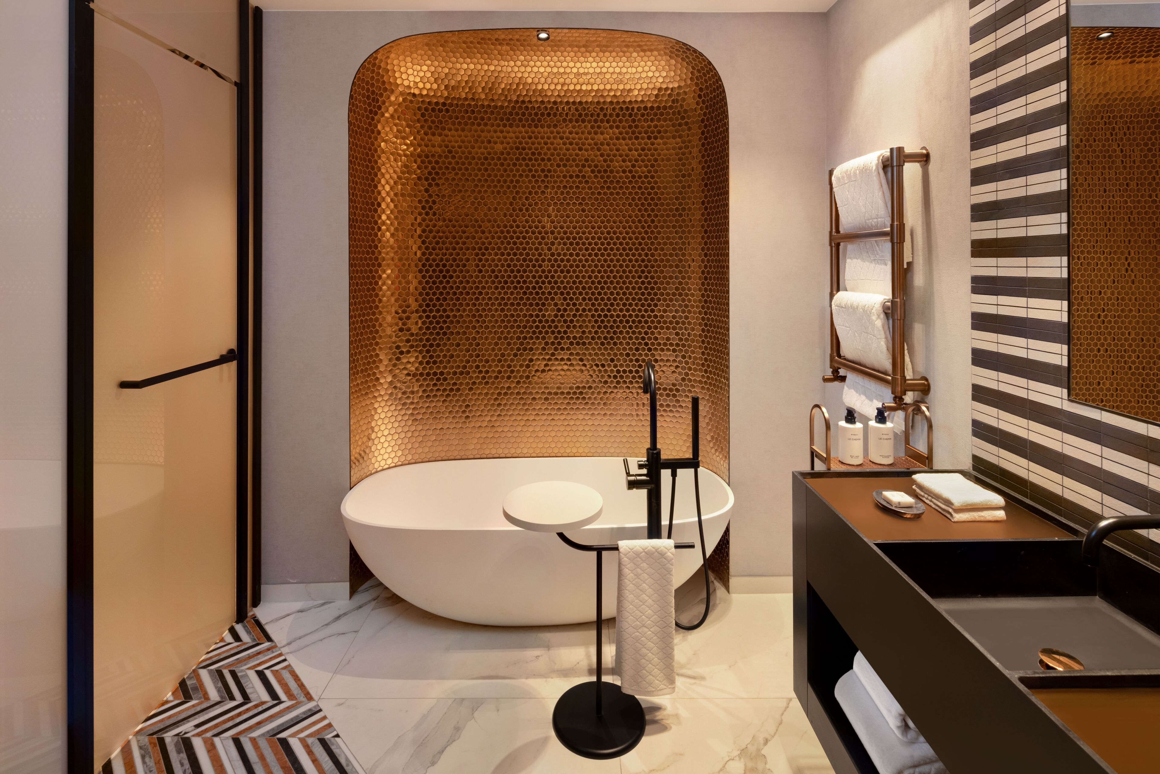 A modern bathroom with a freestanding bathtub, a round sink, and a towel rack.