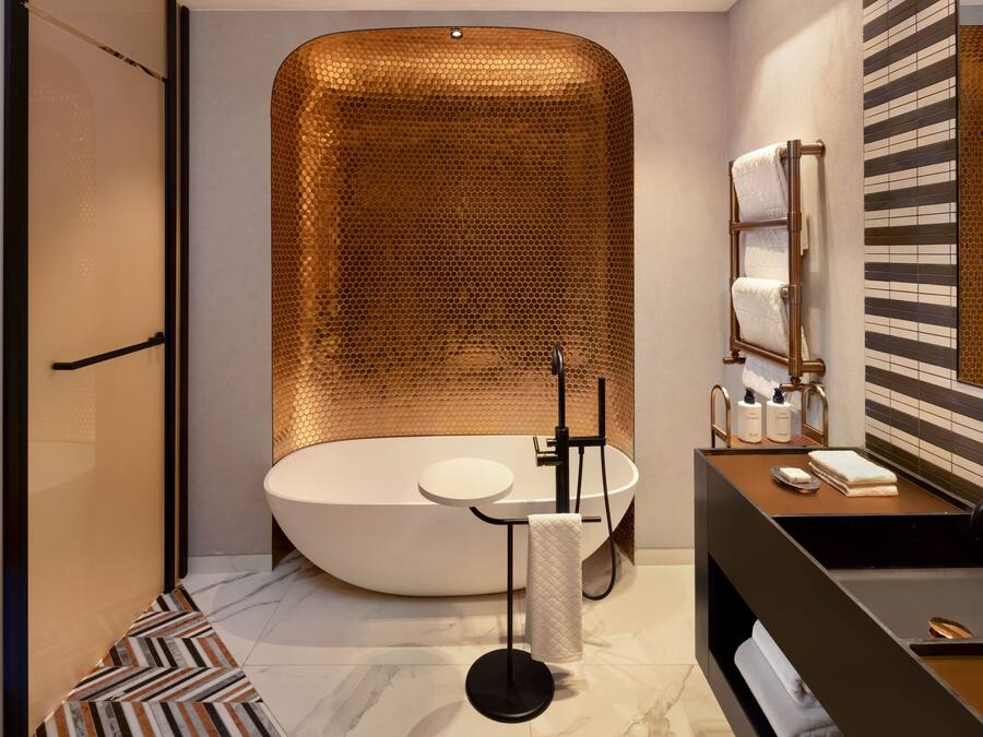 A modern bathroom with a freestanding bathtub, a round sink, and a towel rack.