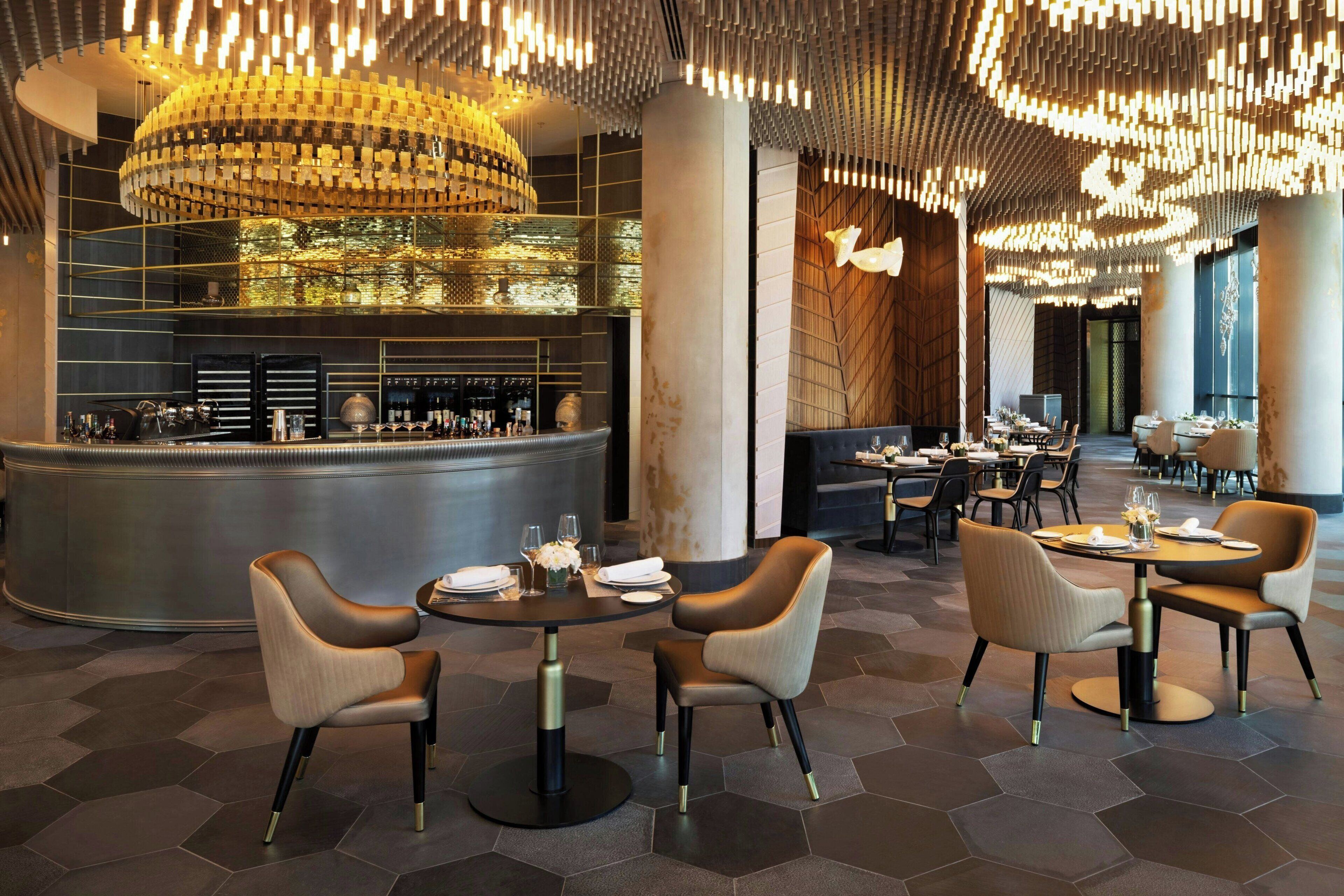 Un restaurante moderno con una barra central, mesas redondas y sillas contemporáneas.
