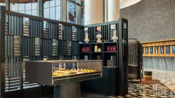 A modern interior with a display case of pastries, a patterned floor, and a wall with a textured design.