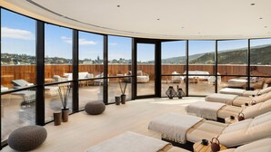 A modern spa with large windows offering city views, a curved ceiling, and a series of massage tables.