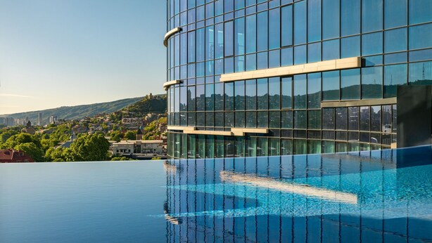 Ein modernes Gebäude mit Glasfassade und Pool auf dem Dach.
