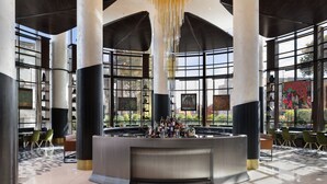 Eine großzügige Lobby mit hohen Decken, großen Fenstern und einer zentralen Bar.