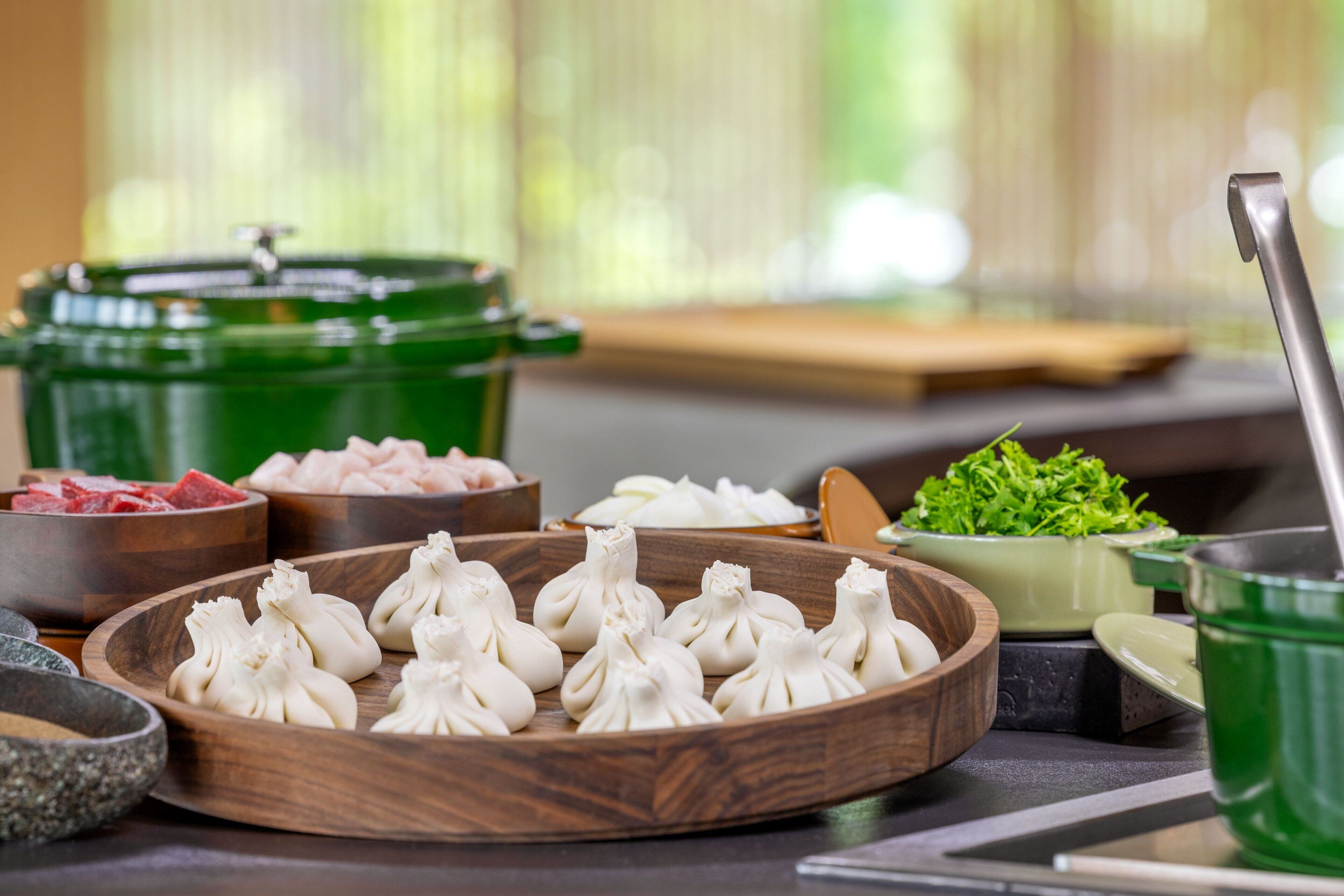 Et spisebord med forskellige retter, herunder dumplings, kød og grøntsager.