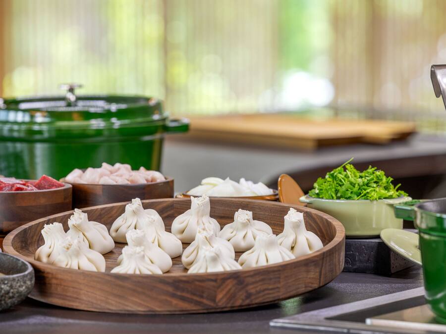 Et spisebord med forskellige retter, herunder dumplings, kød og grøntsager.
