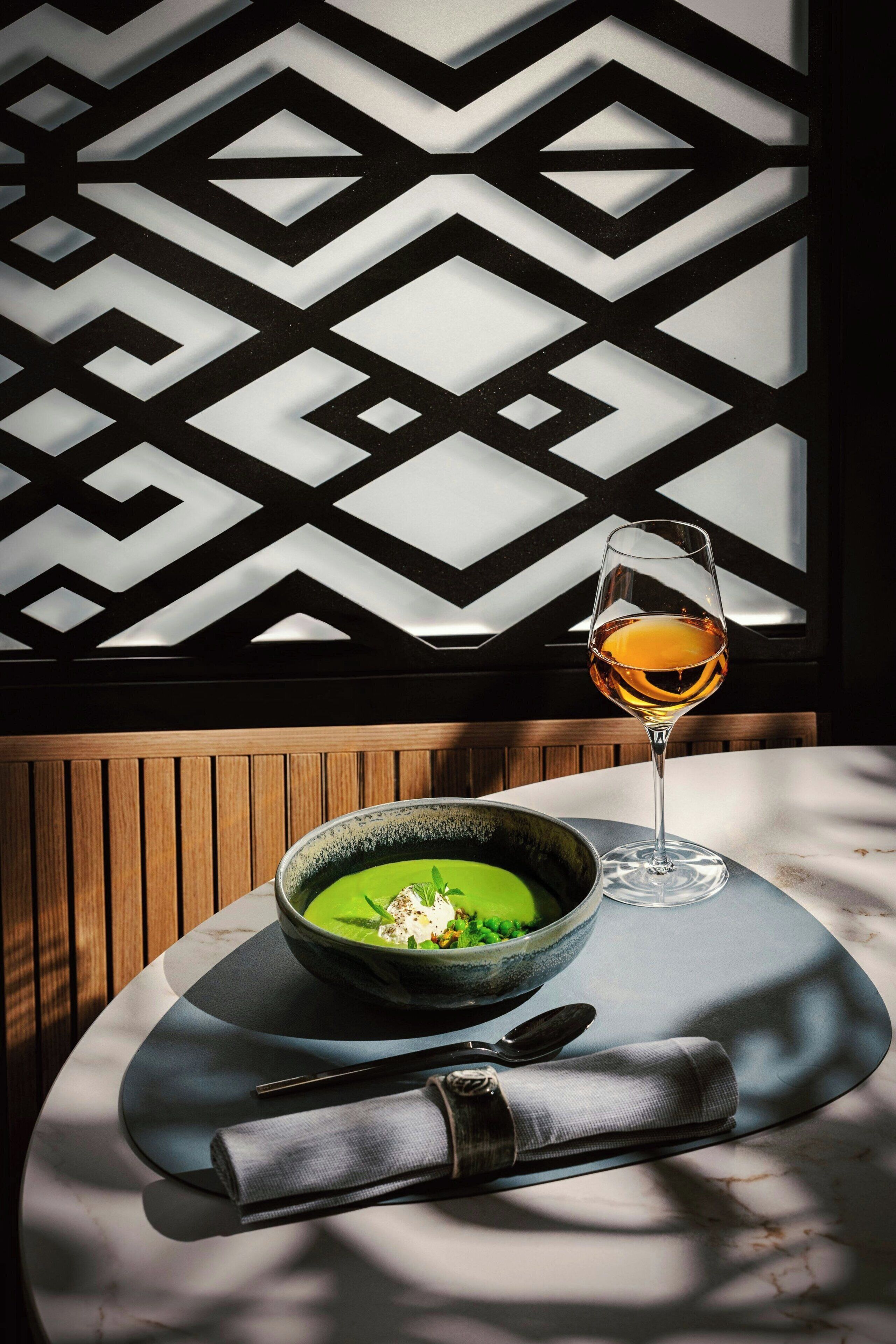 Une table à manger avec un bol de soupe, un verre de vin, des baguettes et une serviette.