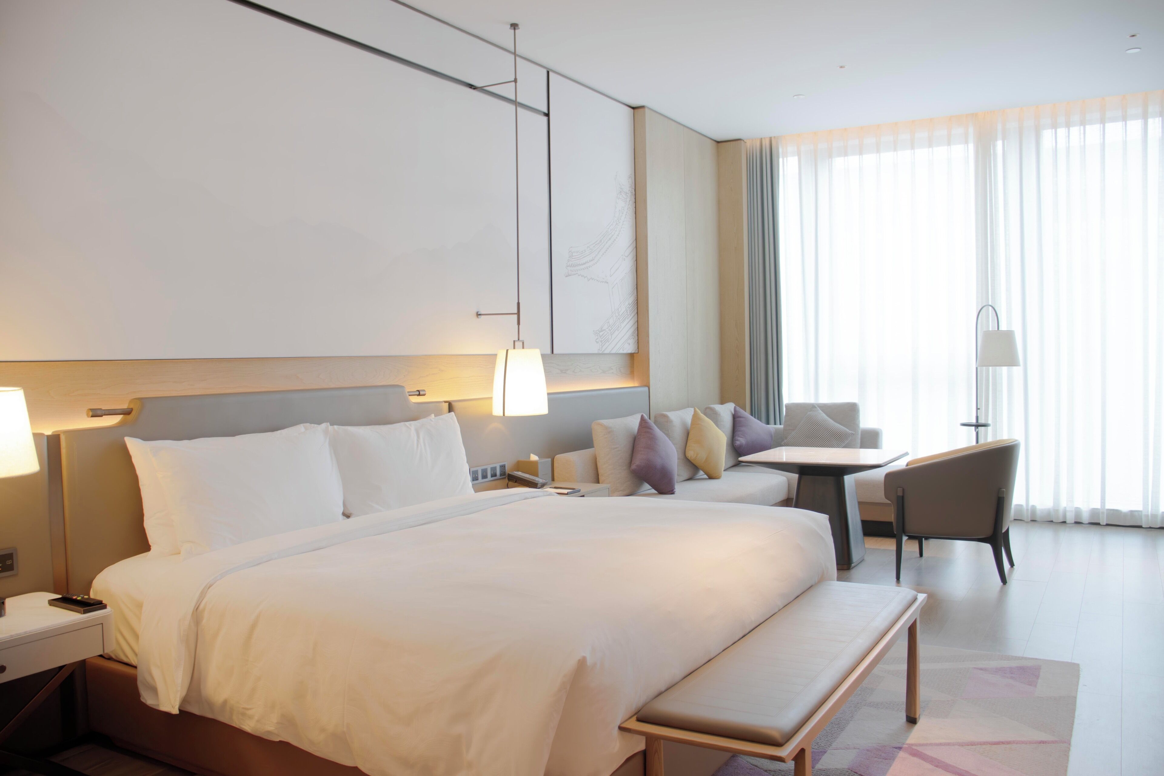 Een moderne hotelkamer met een groot bed, nachtkastjes, een bureau en een stoel.