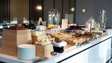 A buffet with various food items and a stack of white plates.